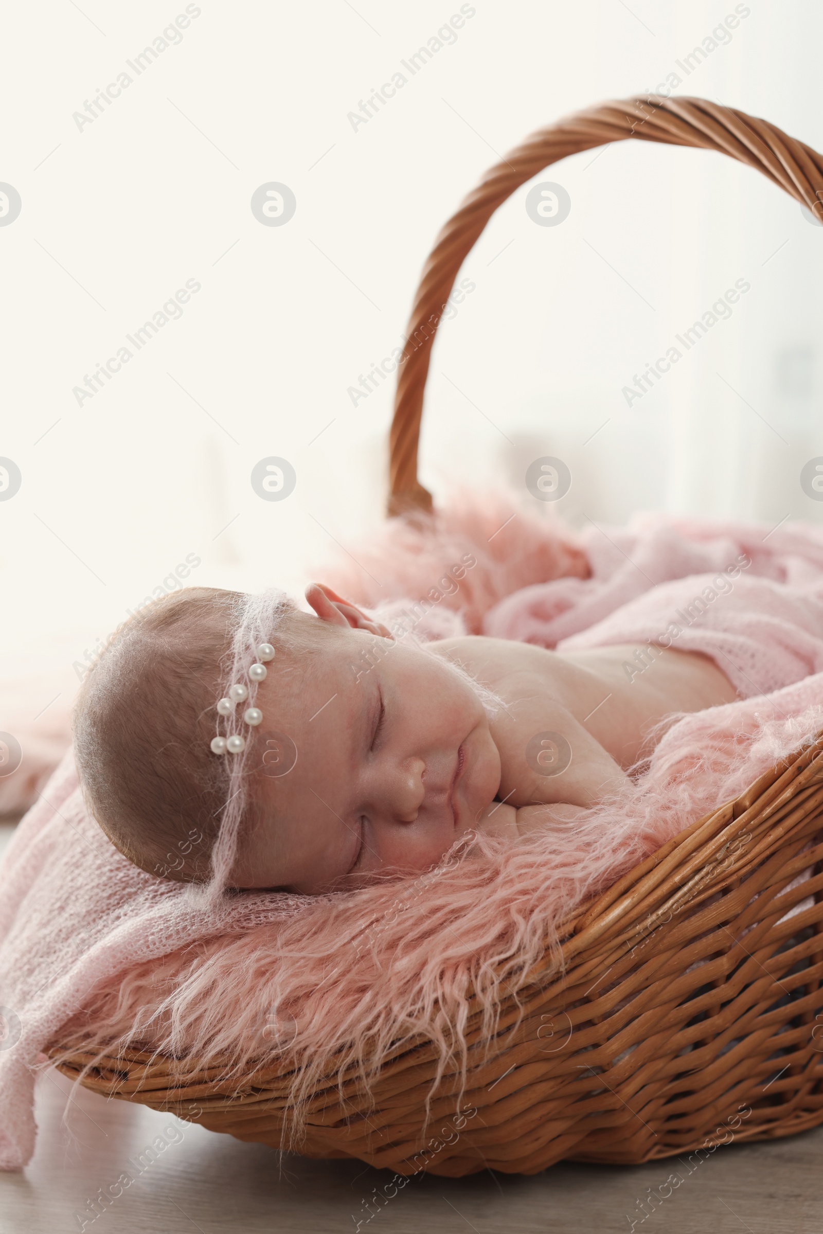 Photo of Adorable little baby sleeping in wicker basket at home