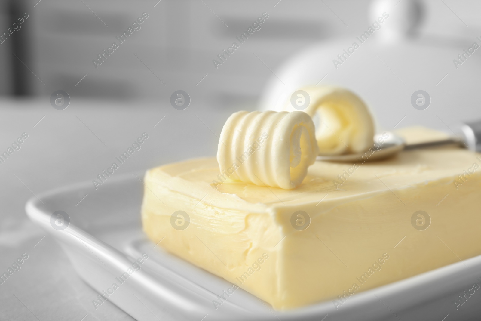 Photo of Dish with piece of butter and curls on table, closeup