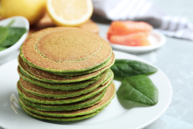 Photo of Tasty spinach pancakes on light grey marble table, closeup