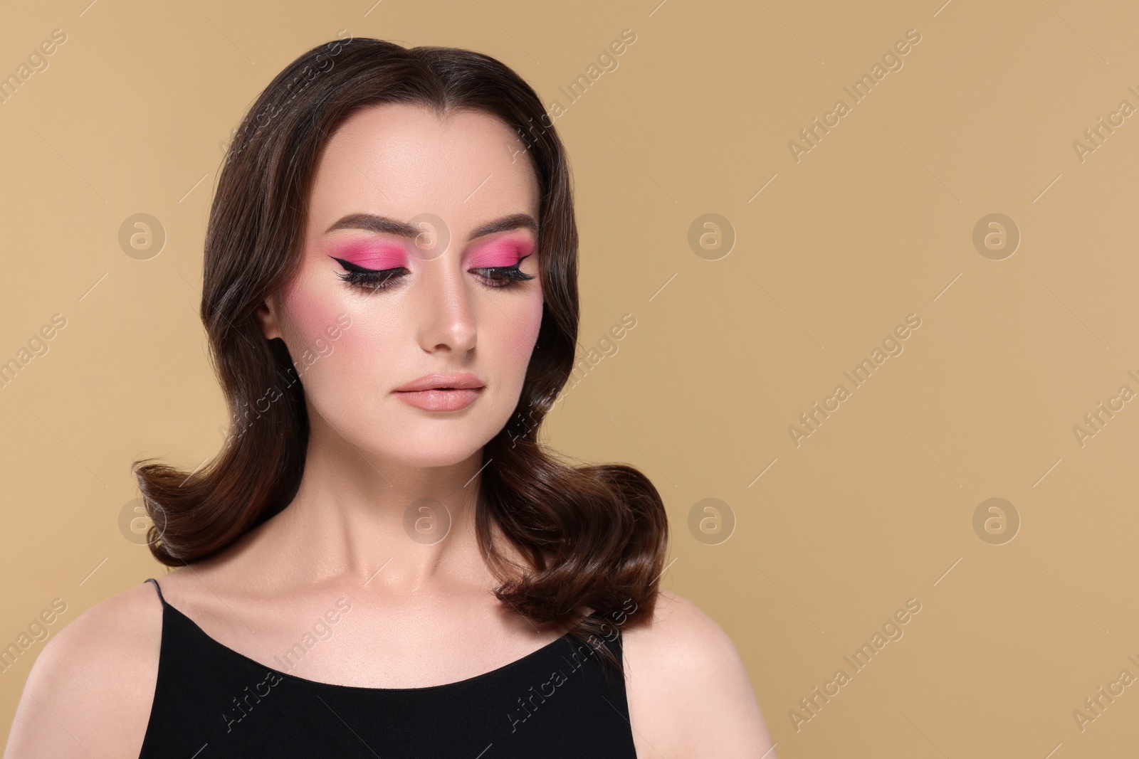 Photo of Portrait of beautiful young woman with makeup and gorgeous hair styling on beige background. Space for text