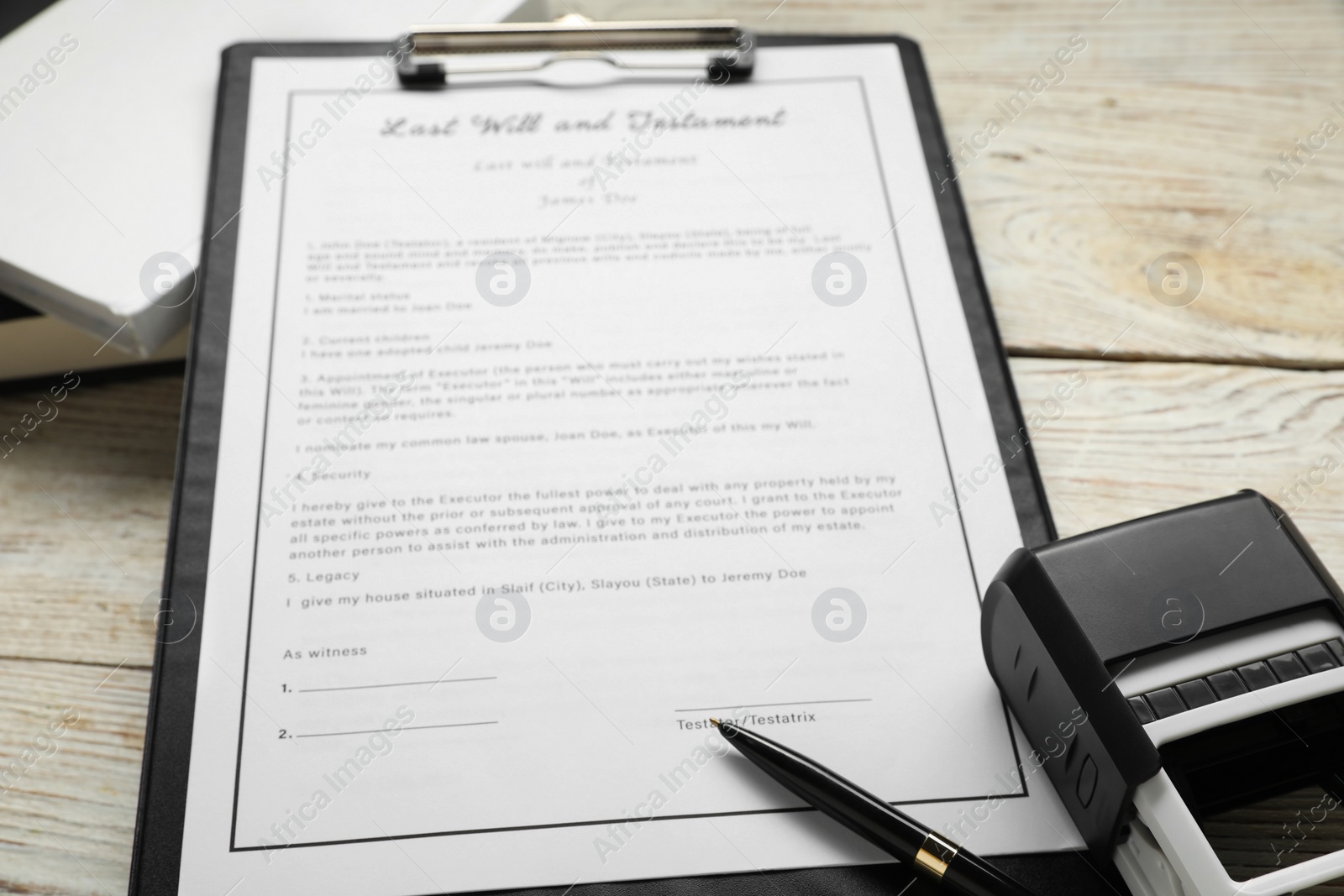 Photo of Last Will and Testament, books, stamp and pen on white wooden table, closeup