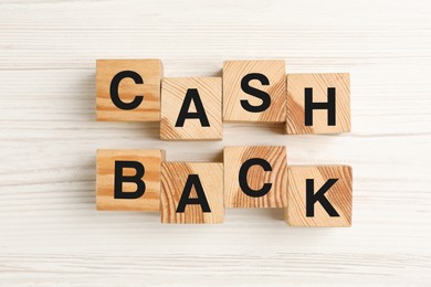 Photo of Cubes with word Cashback on white wooden table, flat lay