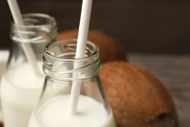 Photo of Glass bottles of delicious coconut milk on table, closeup. Space for text