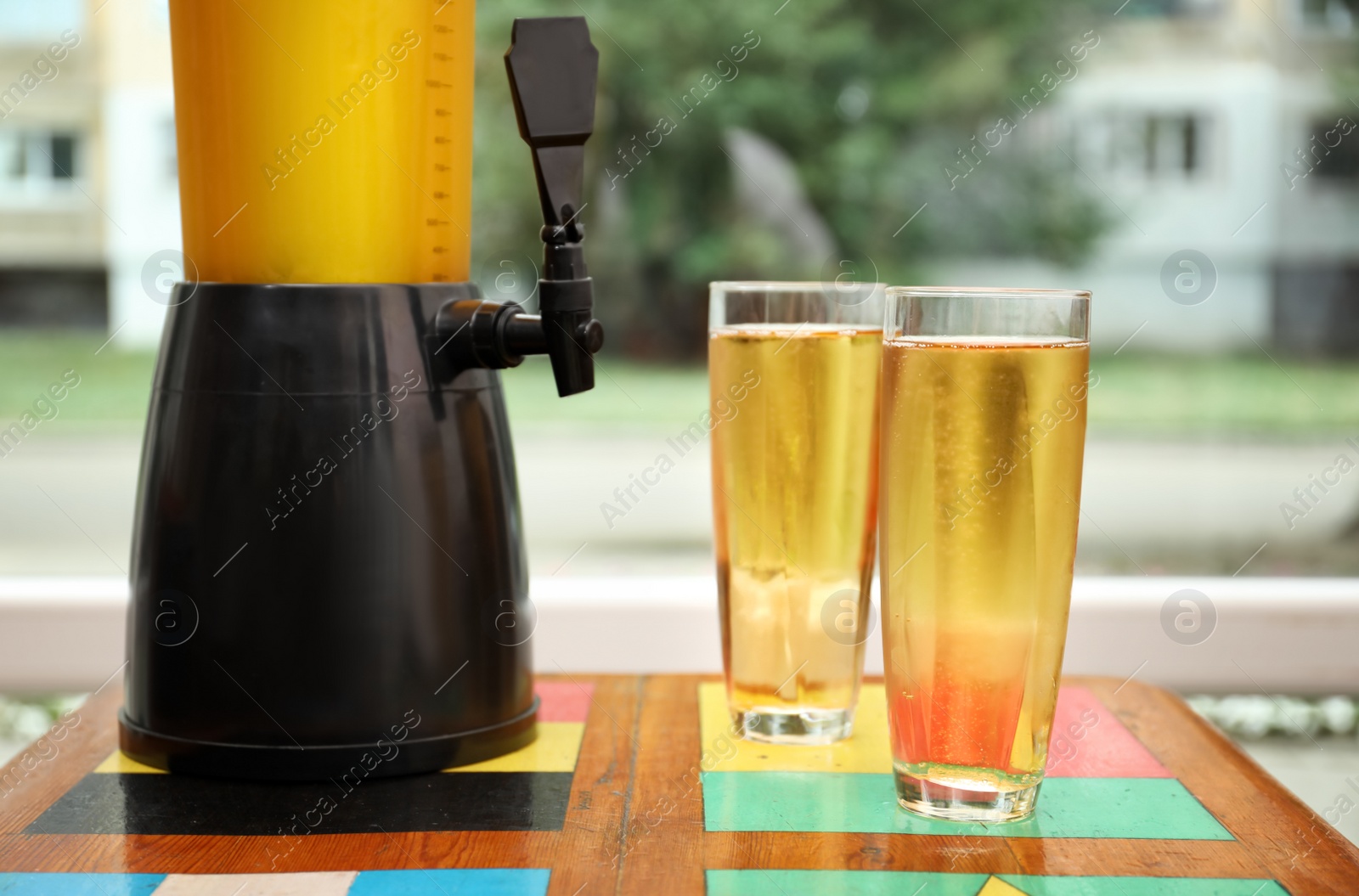 Photo of Dispenser and glasses with cold beer on table