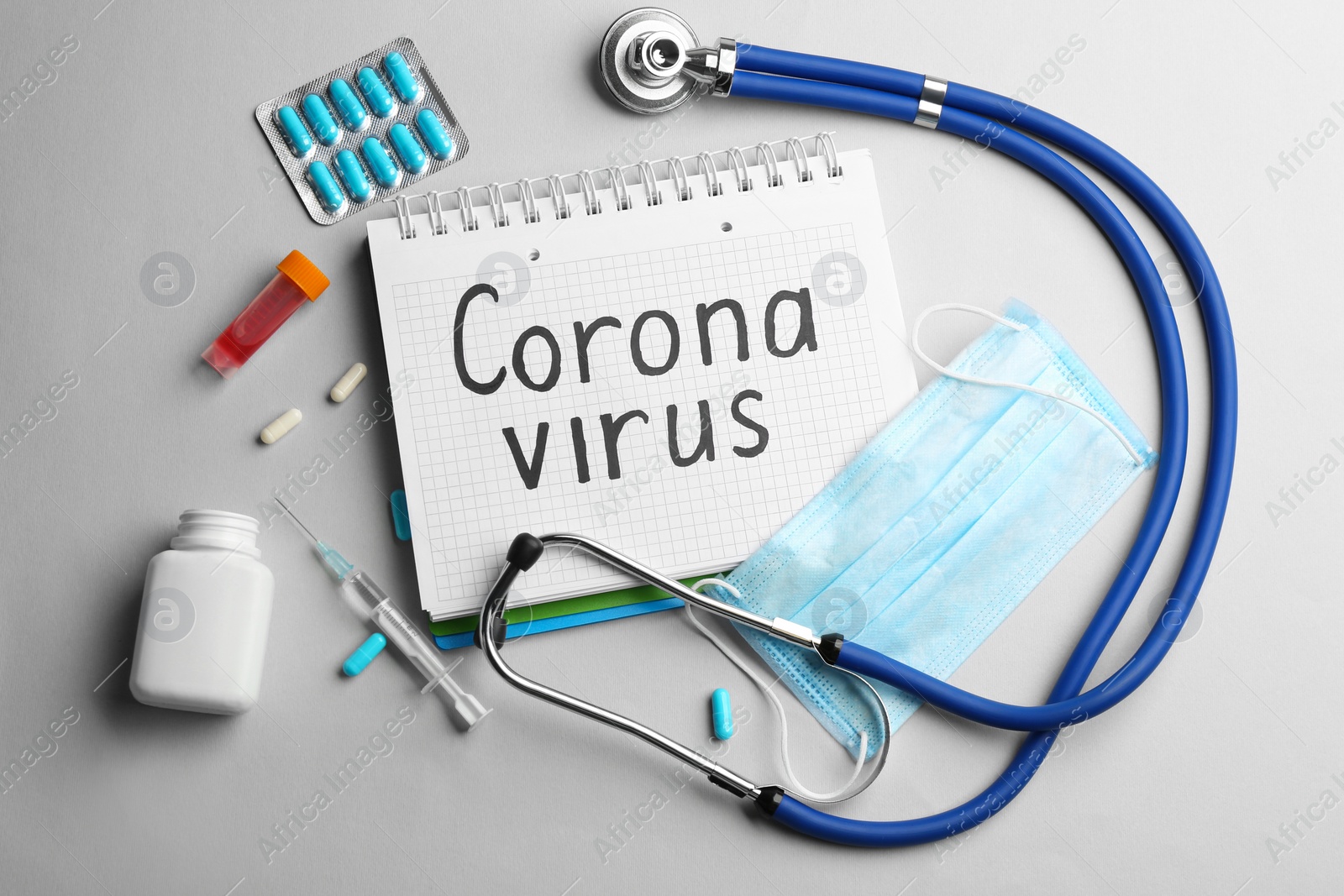Photo of Flat lay composition with words CORONA VIRUS, stethoscope and medicine on light grey background