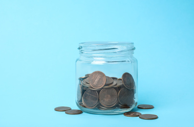 Photo of Glass jar with coins on light blue background