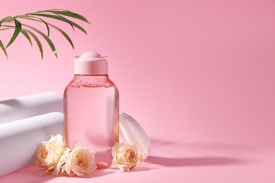 Photo of Bottle of micellar water, roses and cotton pads on pink background. Space for text