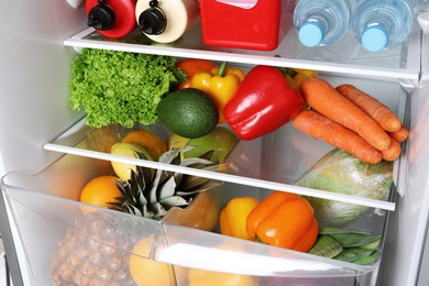 Photo of Open refrigerator with many different products, closeup