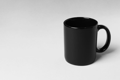 Photo of Black ceramic mug on light grey background. Space for text