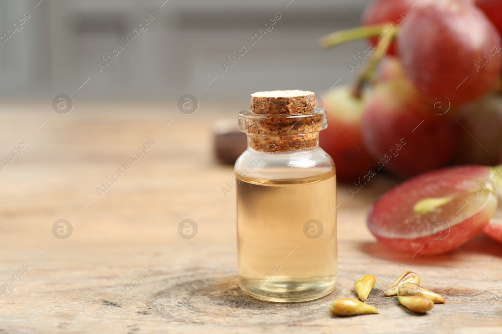 Photo of Natural grape seed oil on wooden table, space for text. Organic cosmetic