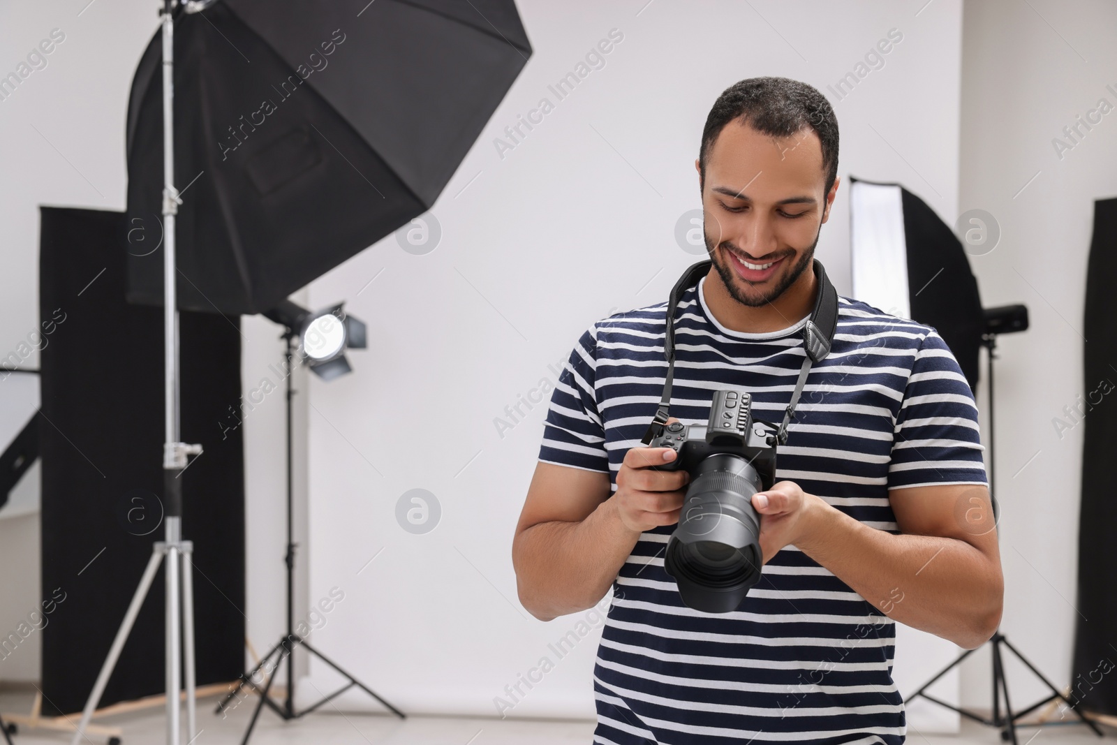 Photo of Young professional photographer with camera in modern photo studio, space for text