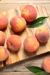 Photo of Fresh peaches and leaves on wooden table, flat lay