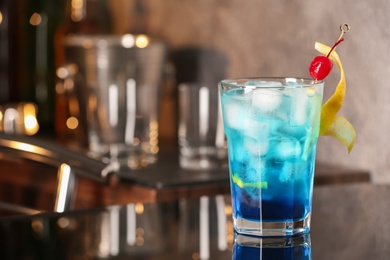 Photo of Blue Lagoon cocktail on black table in bar. Space for text