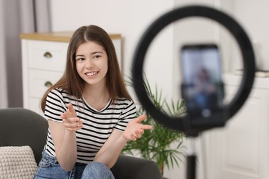 Smiling teenage blogger explaining something while streaming at home