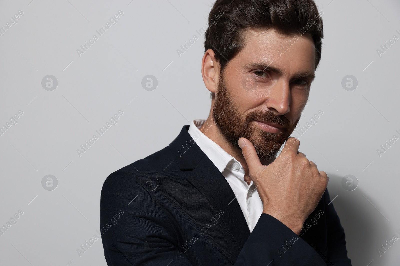 Photo of Portrait of smiling bearded man in suit on light grey background. Space for text