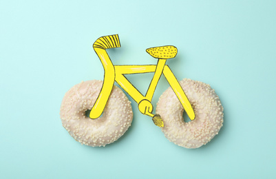 Photo of Bicycle made with donuts and paper on light blue background, top view