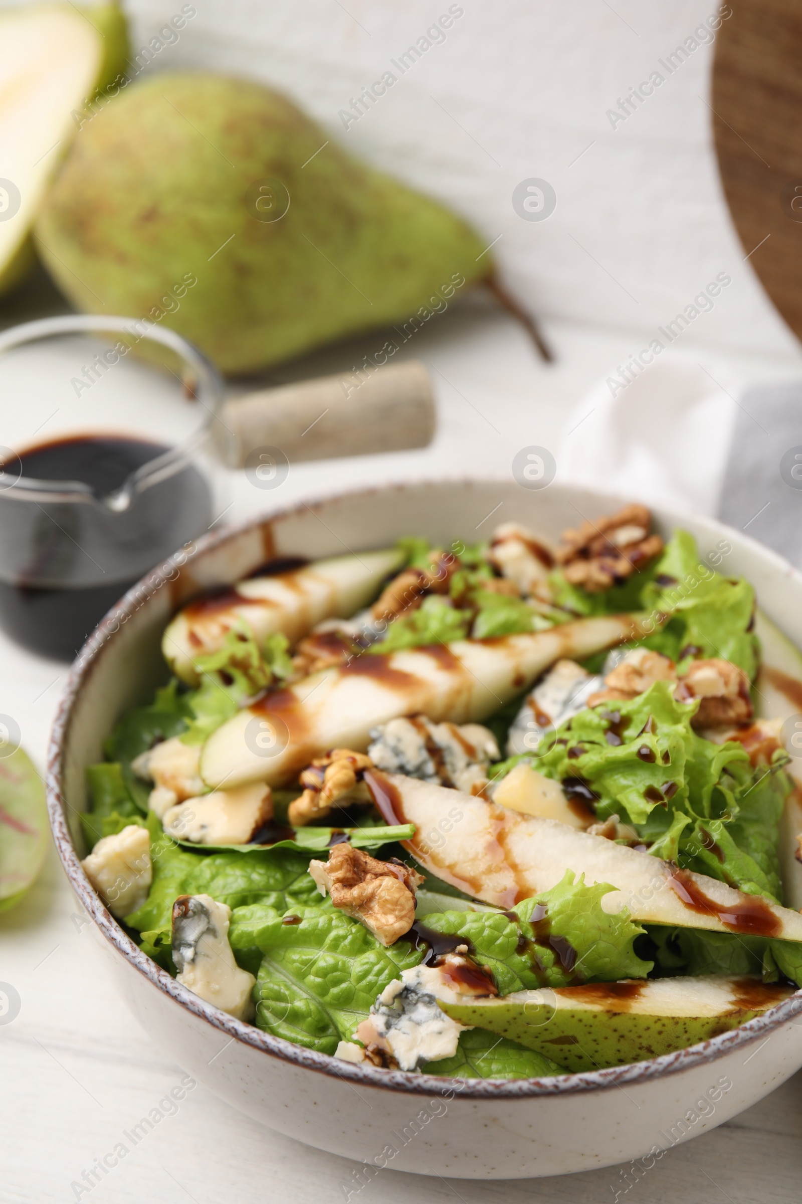 Photo of Delicious pear salad with sauce in bowl on white wooden table, closeup