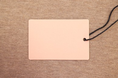 Photo of Cardboard tags on brown garment, top view. Space for text