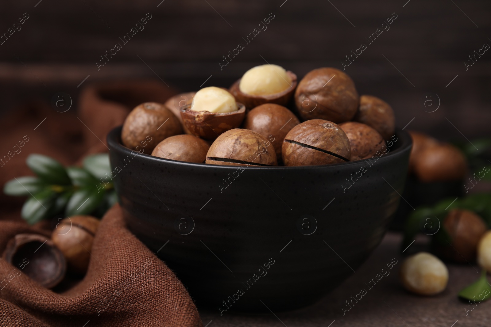 Photo of Tasty Macadamia nuts in bowl on table, closeup