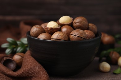 Tasty Macadamia nuts in bowl on table, closeup