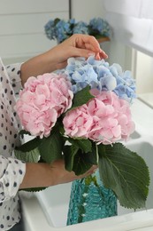 Photo of Woman with beautiful hortensia flowers in kitchen, closeup