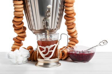 Samovar with hot tea, jam and delicious ring shaped Sushki (dry bagels) on table against white background