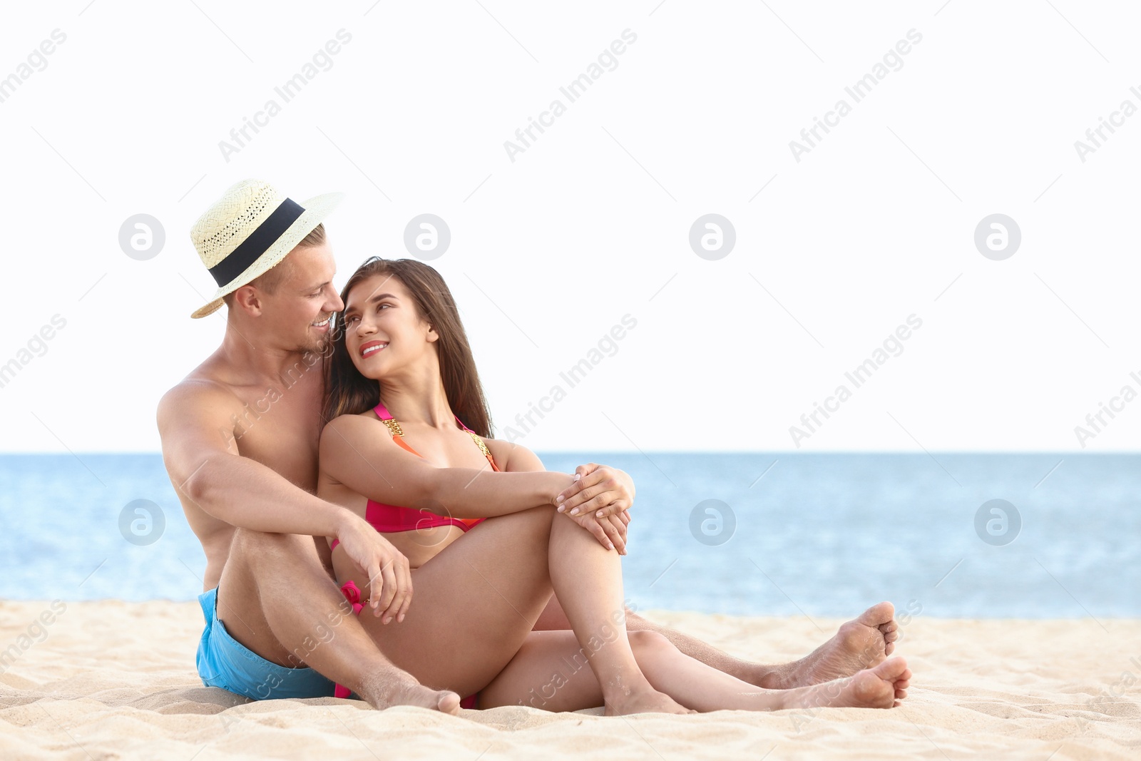 Photo of Young woman in bikini spending time with her boyfriend on beach. Lovely couple