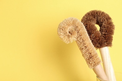 Photo of Cleaning brushes on yellow background, space for text. Dish washing supplies