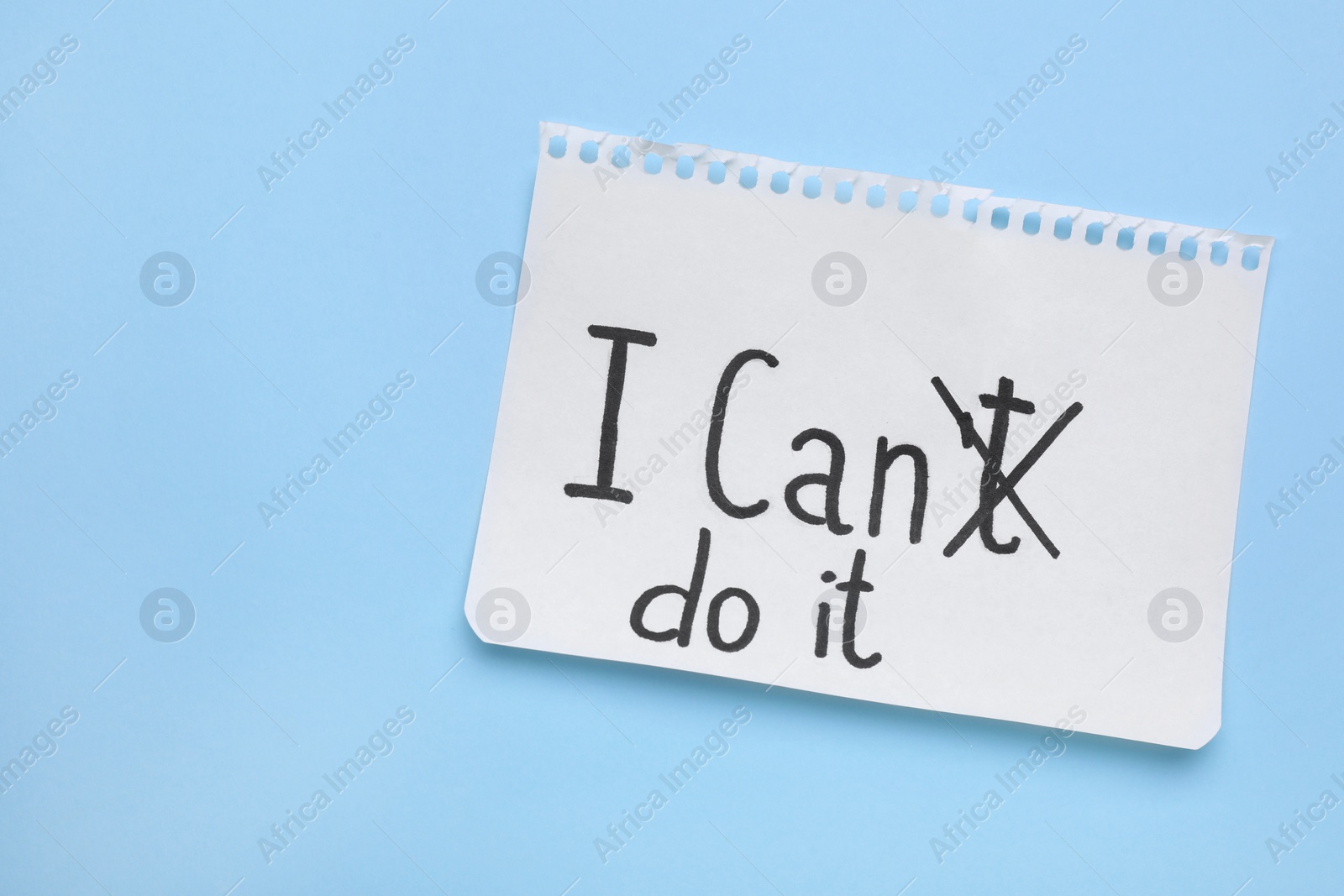 Photo of Motivation concept. Changing phrase from I Can't Do It into I Can Do It by crossing out letter T on light blue background, top view. Space for text