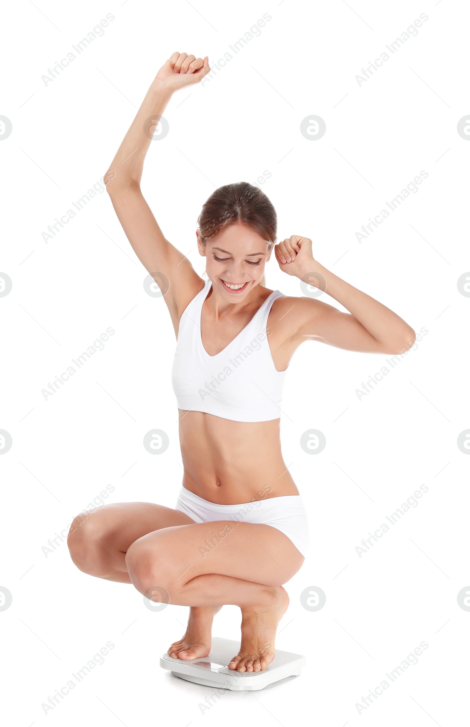 Photo of Happy young woman satisfied with her diet results using bathroom scales on white background