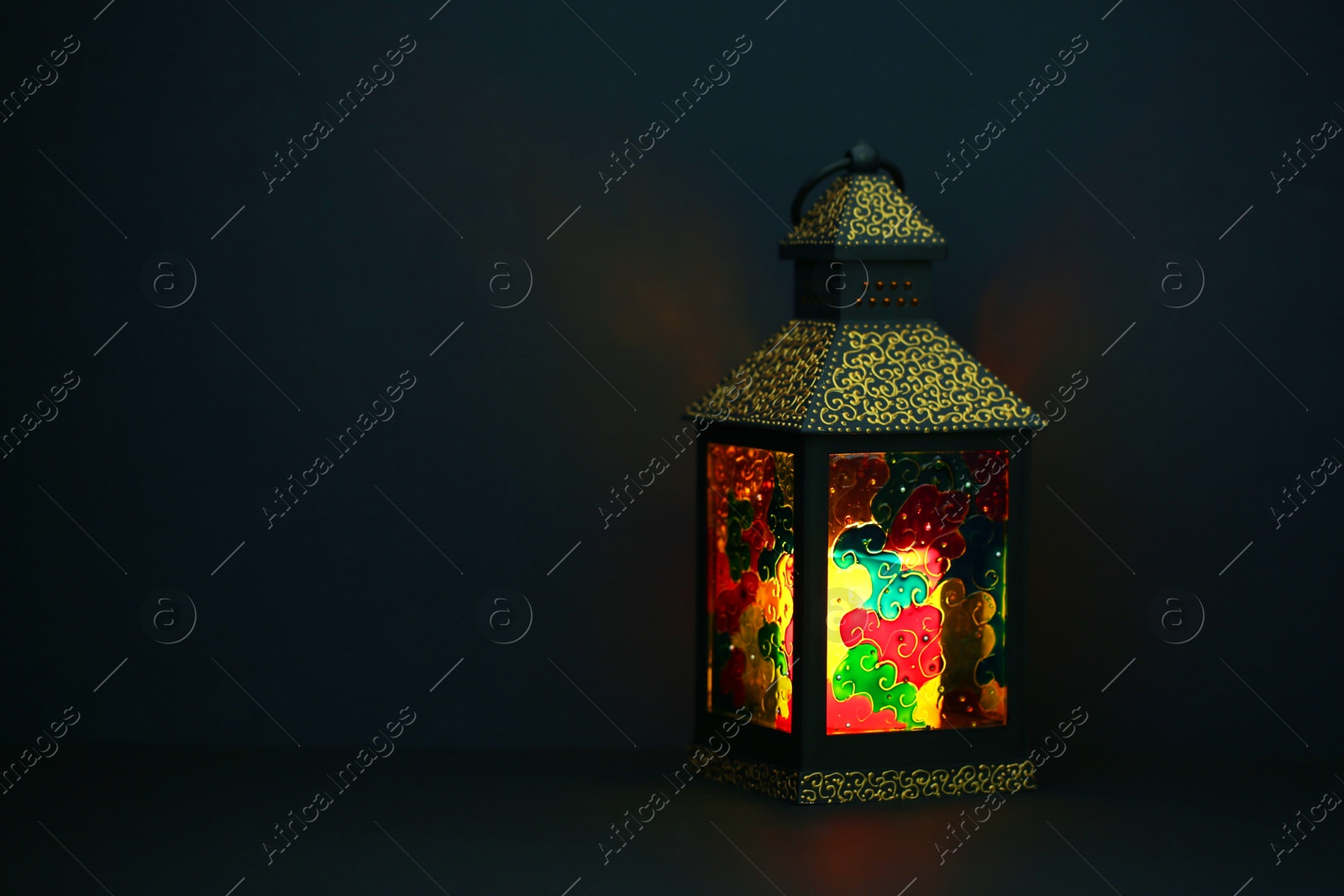 Photo of Decorative Arabic lantern on table against dark background. Space for text