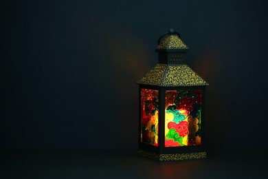 Photo of Decorative Arabic lantern on table against dark background. Space for text