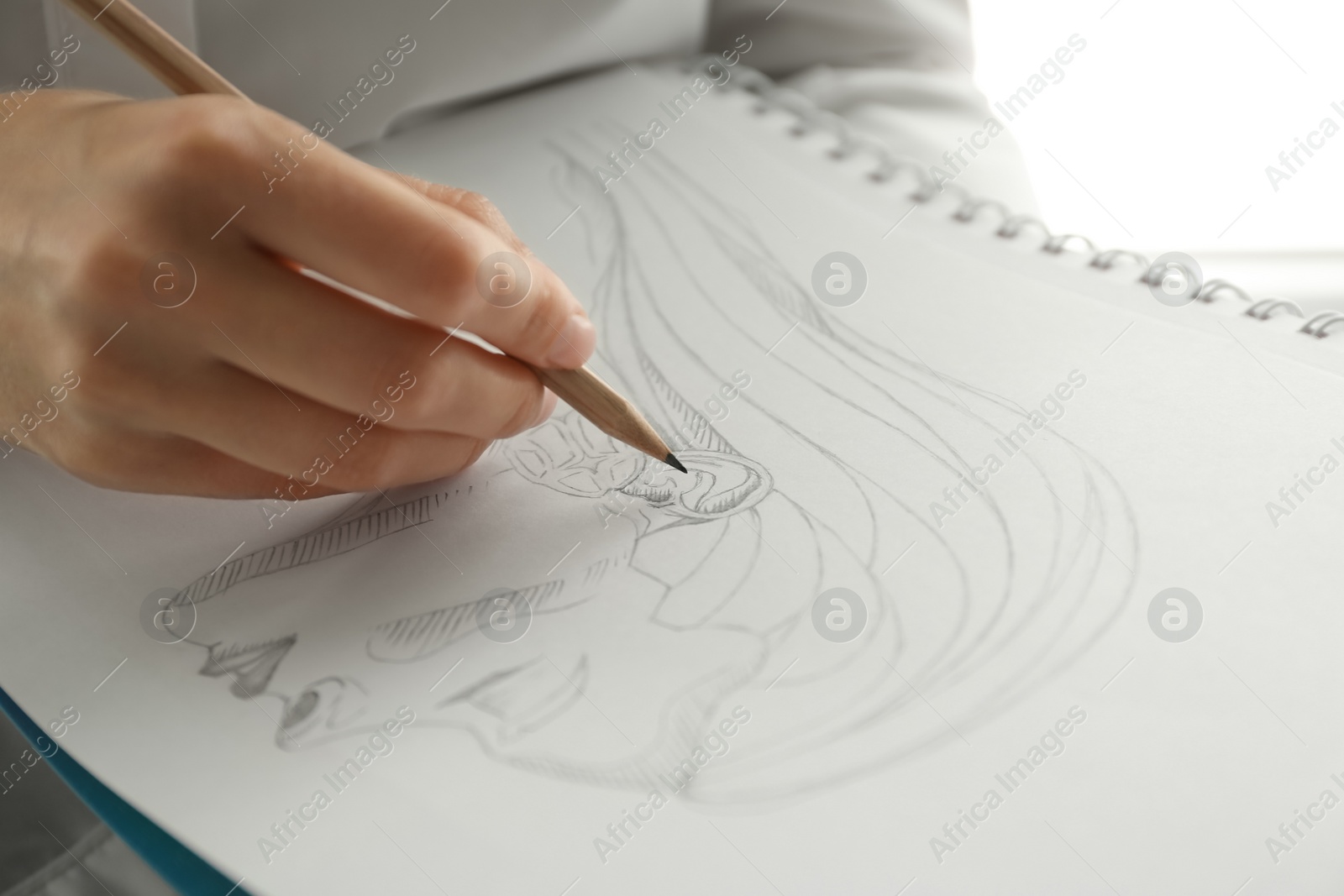 Photo of Woman drawing girl's portrait with pencil in notepad, closeup