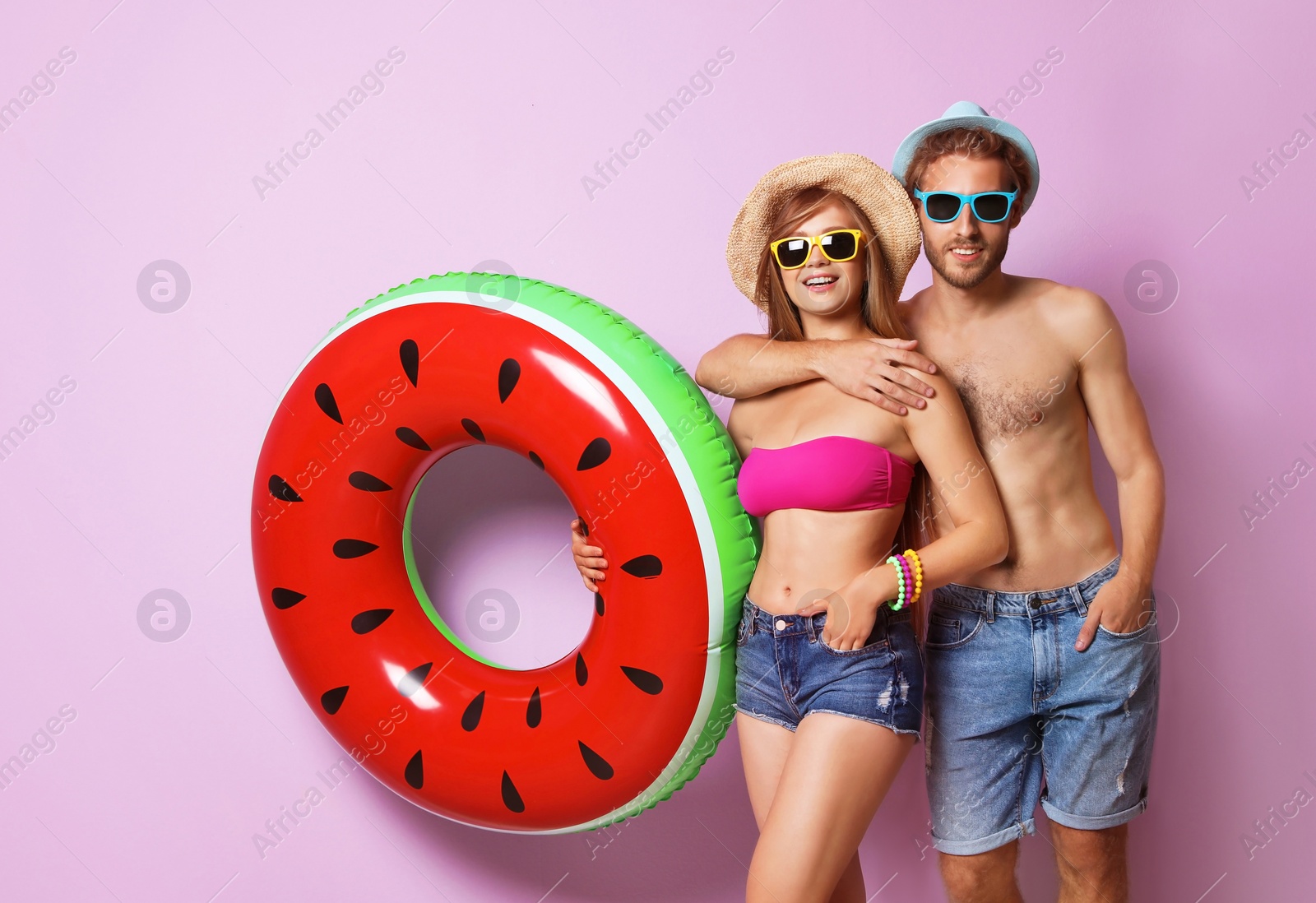 Photo of Young couple in beachwear with inflatable ring on color background