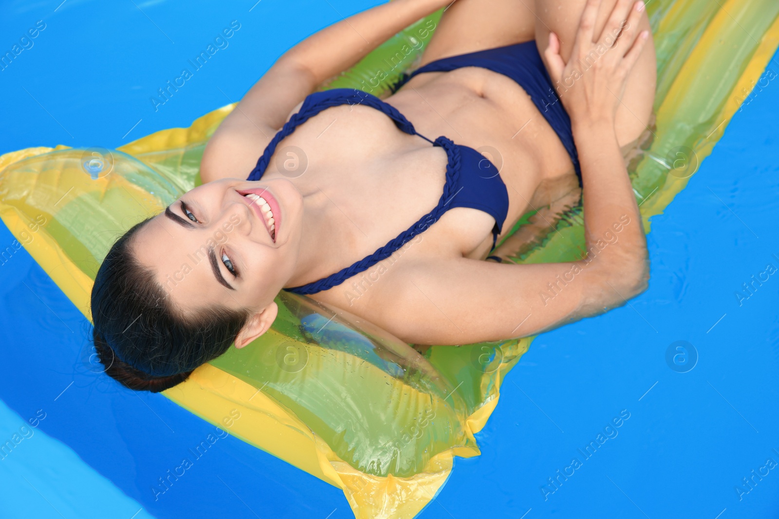 Photo of Beautiful young woman wearing bikini on inflatable mattress in swimming pool