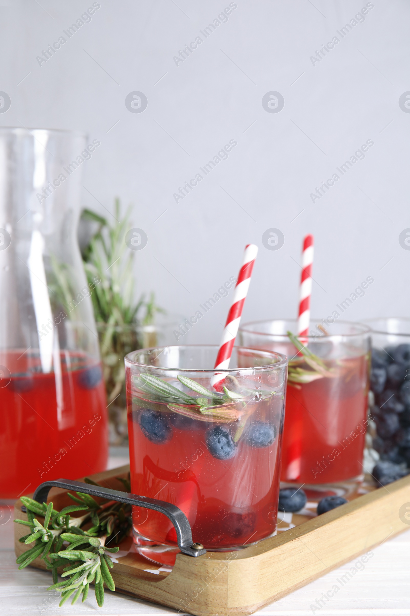 Photo of Tasty refreshing blueberry cocktail with rosemary on table