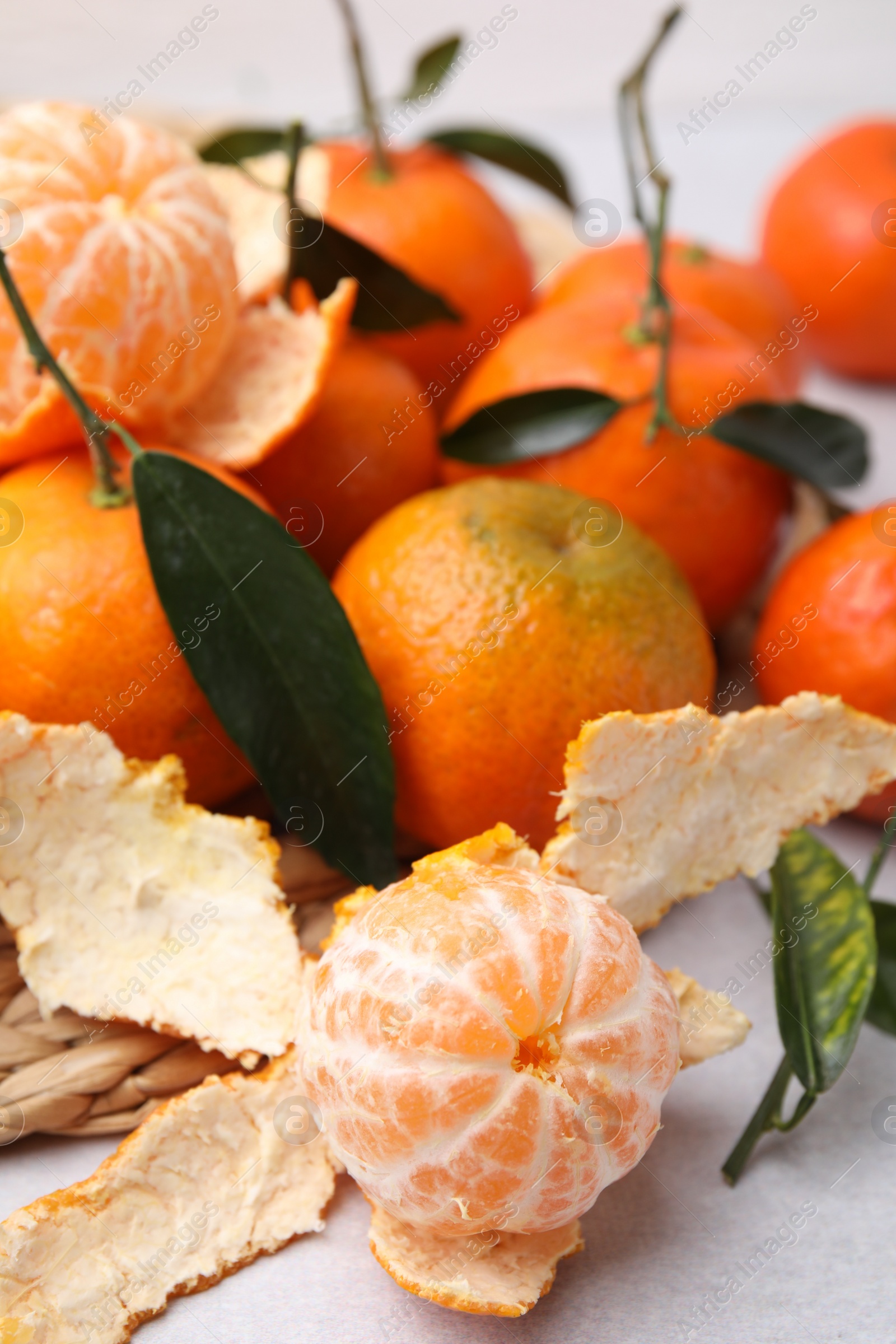 Photo of Many fresh ripe tangerines and leaves on white table, closeup