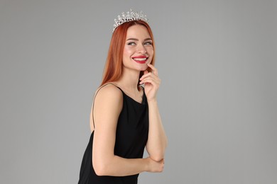 Beautiful young woman with tiara in dress on light grey background, space for text