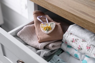 Beautiful heart shaped scented wax sachet and clothes in dresser drawer indoors, closeup