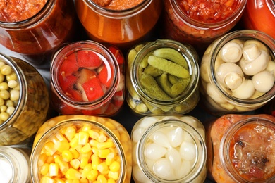 Open jars with pickled vegetables on grey table, flat lay