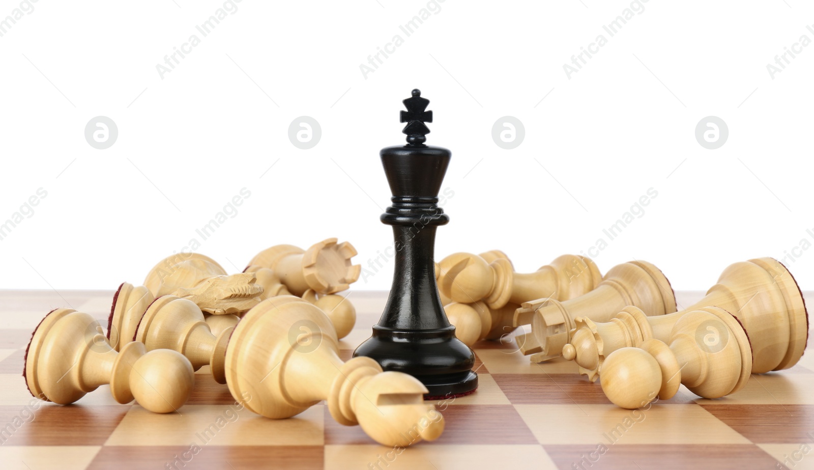 Photo of King among fallen chess pieces on wooden board against white background