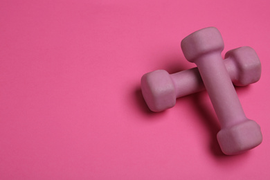 Photo of Modern dumbbells on pink background. Space for text