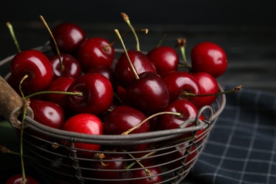 Photo of Metal basket with ripe sweet cherries on dark table, closeup