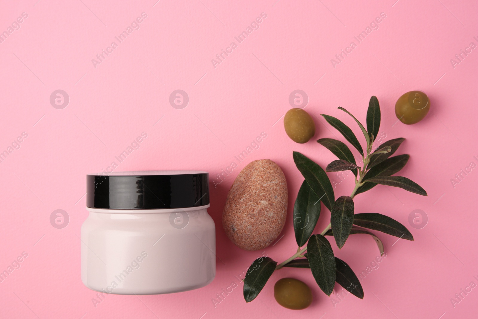 Photo of Natural cosmetic. Olive cream, pebble stone and ingredient on pink background, flat lay. Space for text