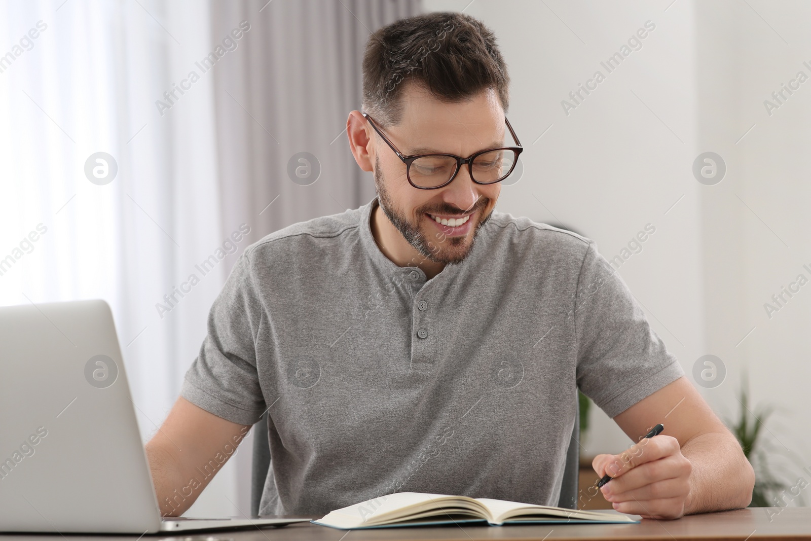 Photo of Online translation course. Man writing near laptop at home