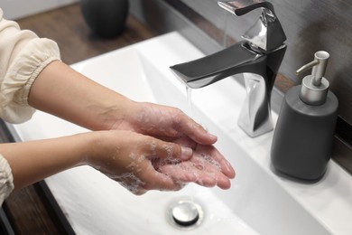 Photo of Woman washing hands in bathroom, closeup view