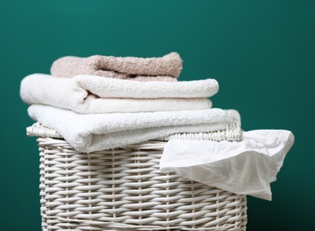 Wicker laundry basket with dirty clothes and clean towels on color background