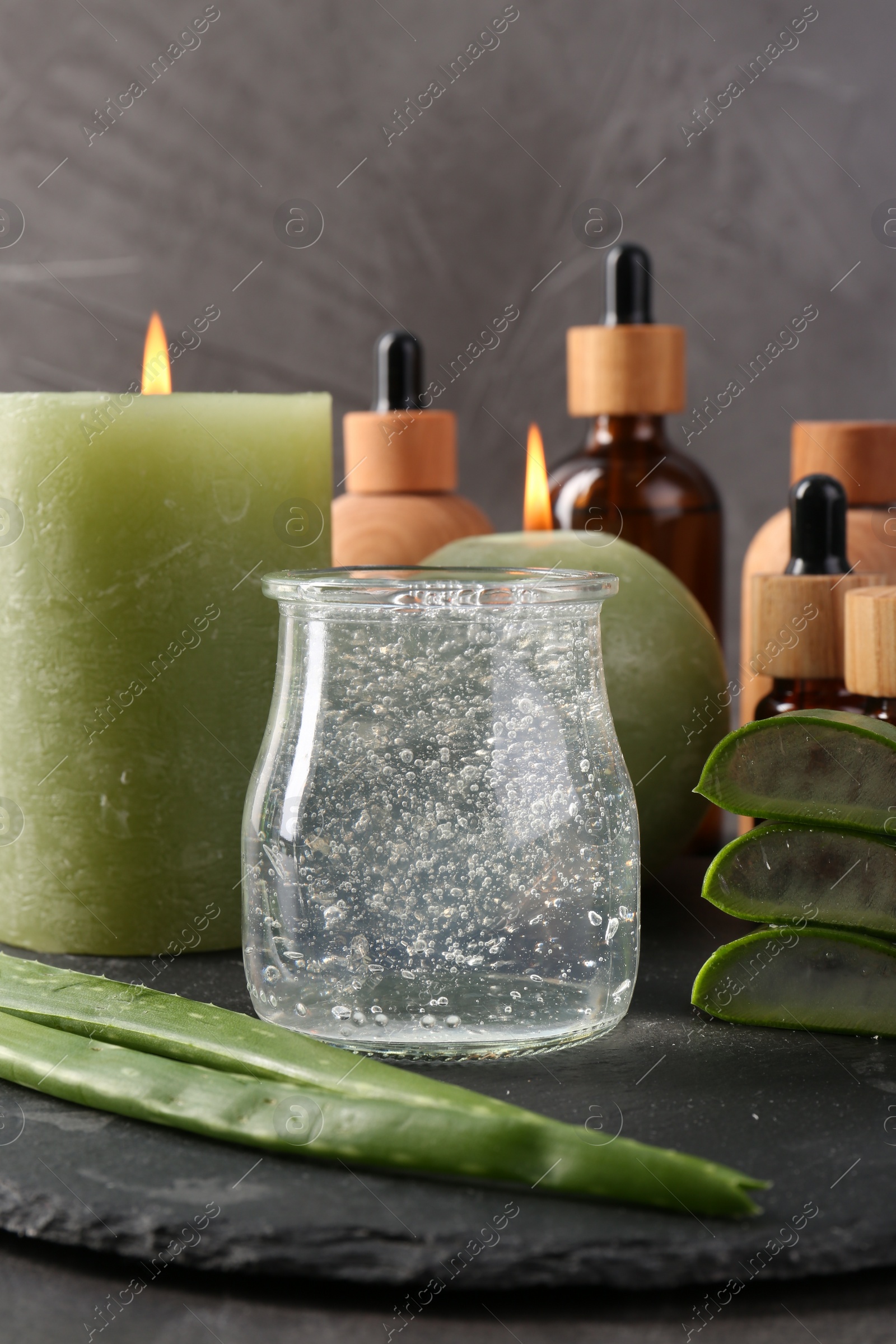 Photo of Cosmetic products, burning candles, aloe vera leaves and gel on table