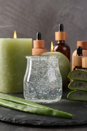 Cosmetic products, burning candles, aloe vera leaves and gel on table