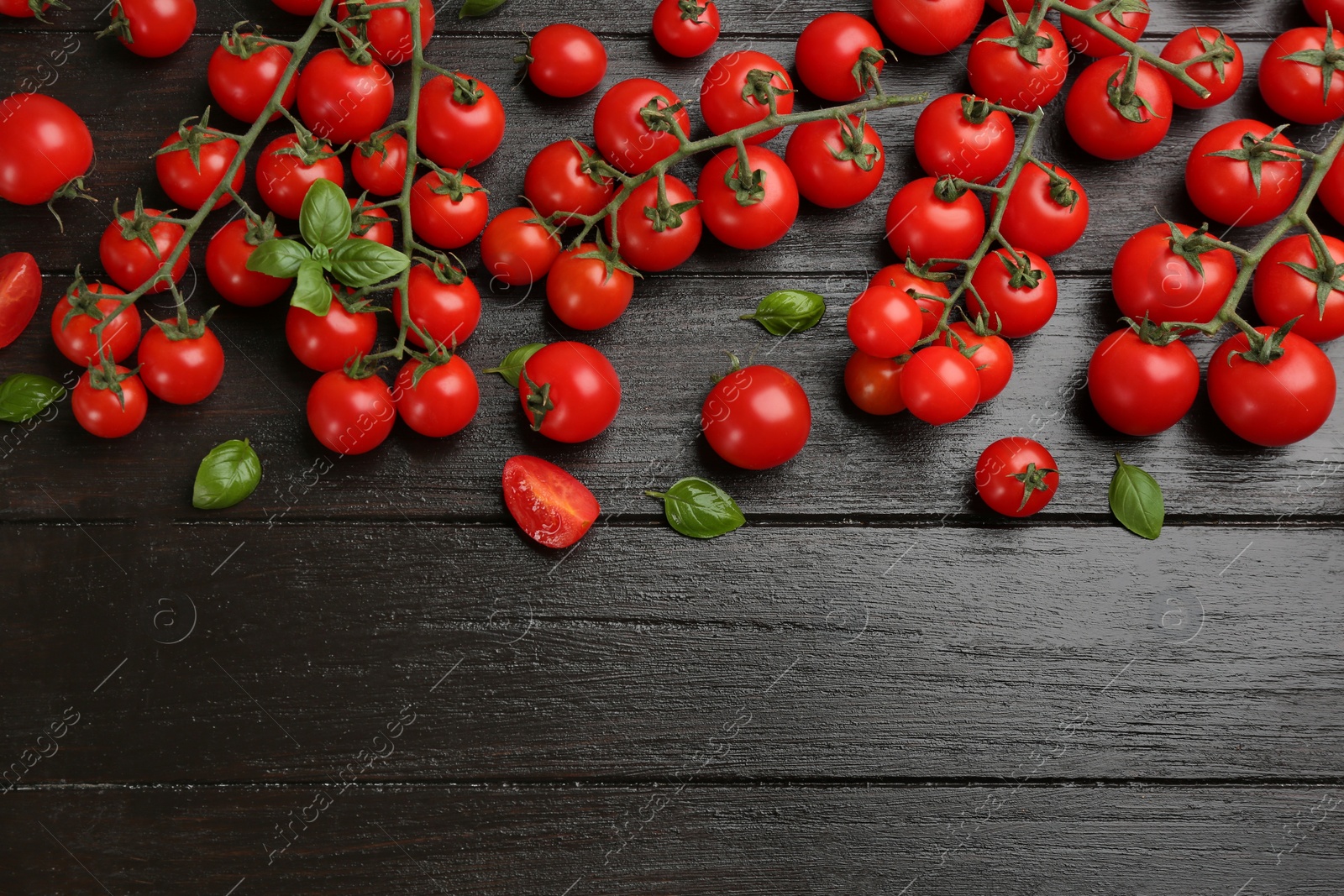 Photo of Fresh cherry tomatoes and basil leaves on black wooden table, flat lay. Space for text